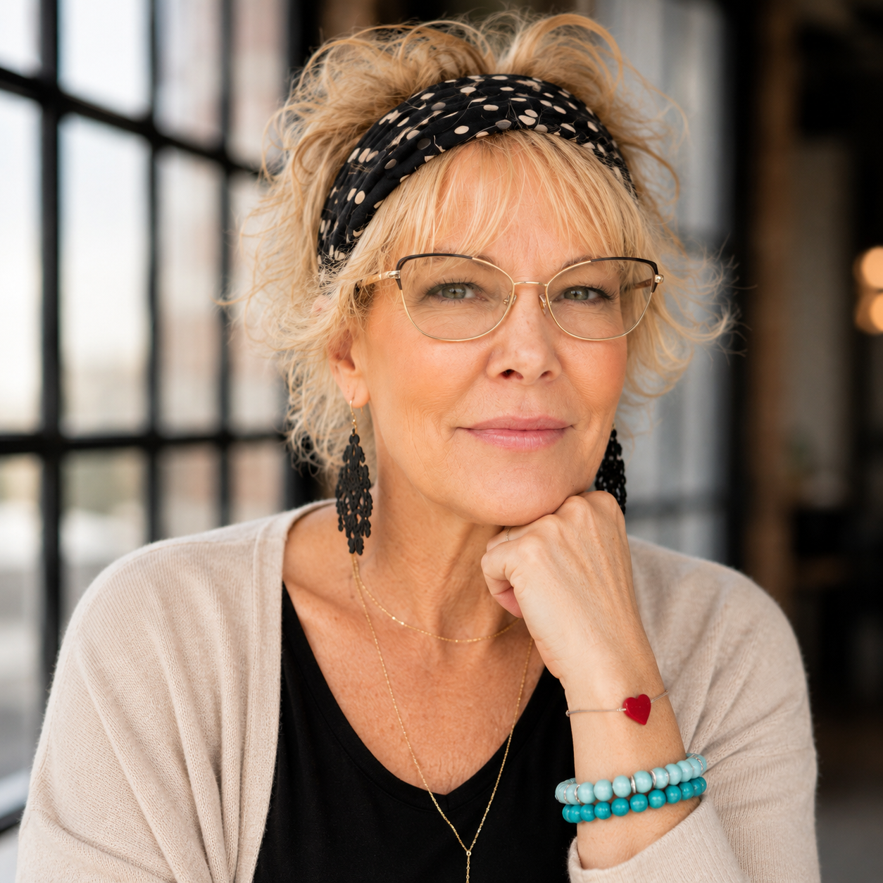 Aimee Meek seated thoughtfully by a loft window with her hand resting beneath her chin.